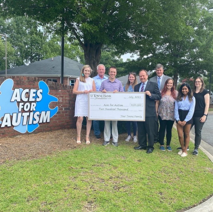 Group of nine people standing together holding a large donation check.