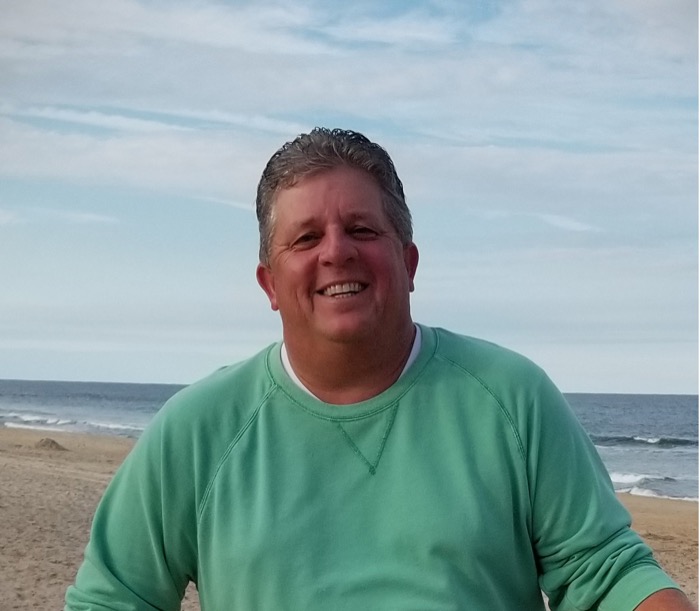 Photo of Doug Sims with oceanfront in background.