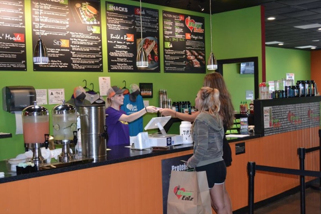 Restaurant cashier greeting customers at counter.