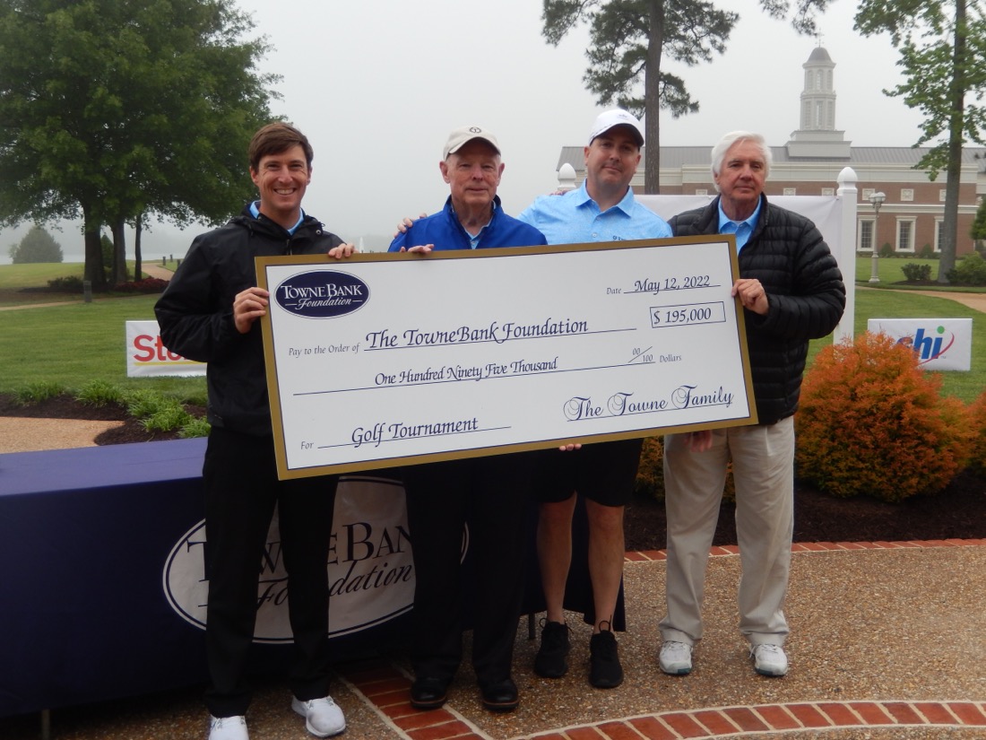 Four people posing with a large donation check.