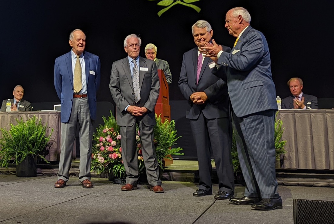 Group of four people standing on a stage and talking.