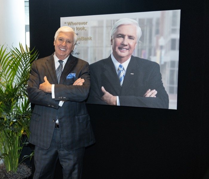 Photo of man standing next to a photo of himself mimicking the same pose.